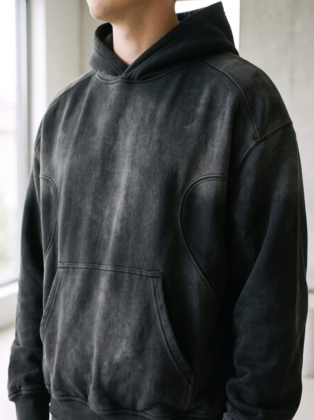 Sunfaded monochrome hoodie worn by a model, close up on the seam design