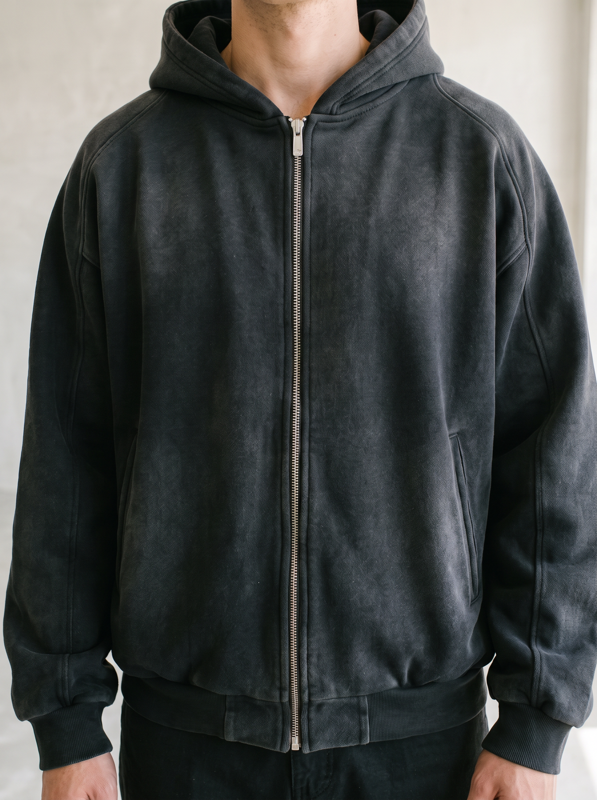 Sunfaded black zip up hoodie worn by a model, close up on the cropped fit