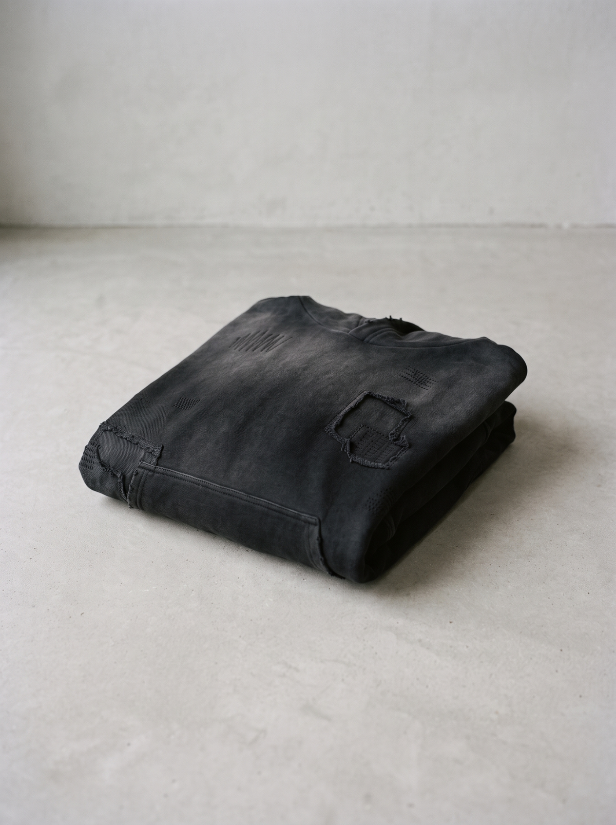 Sashiko stitched hoodie folded on a smooth concrete floor