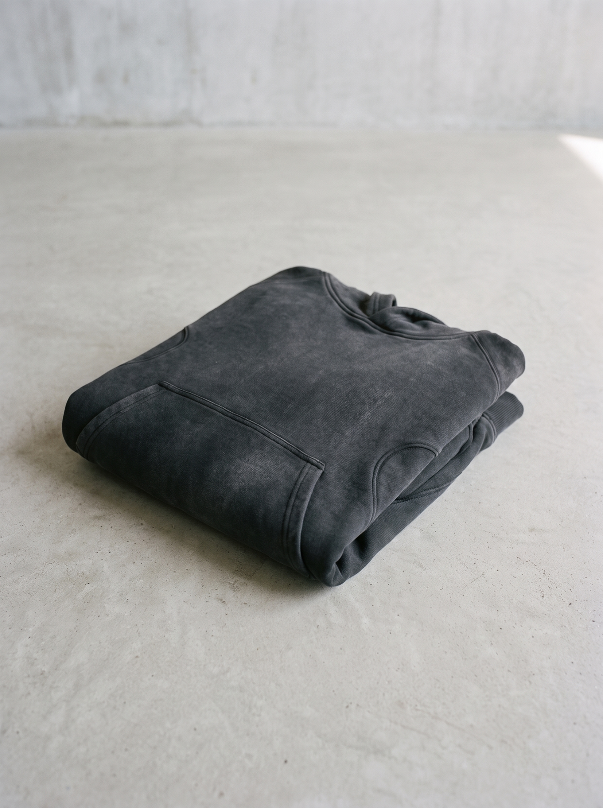 Washed heavyweight cropped hoodie folded on a smooth concrete floor
